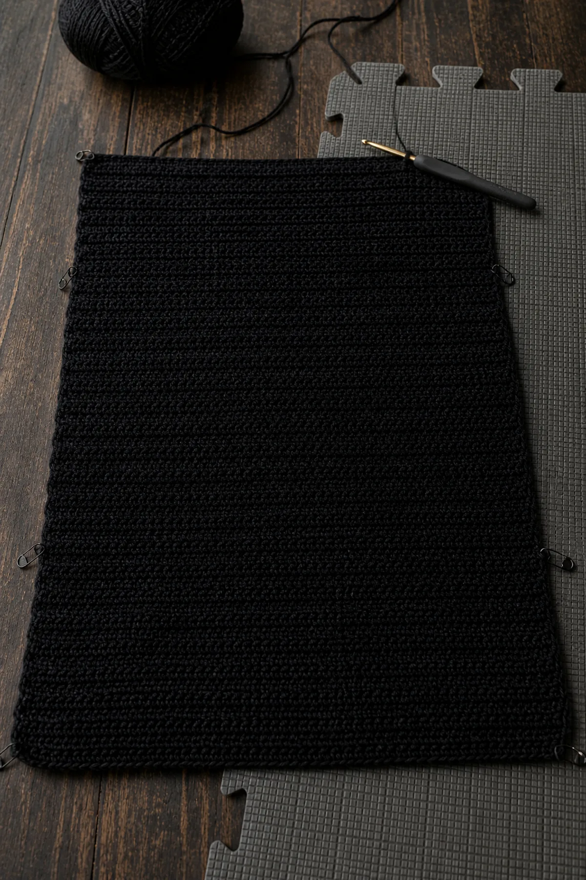Black 72-stitch crochet cardigan back panel in progress with neat half double crochet rows