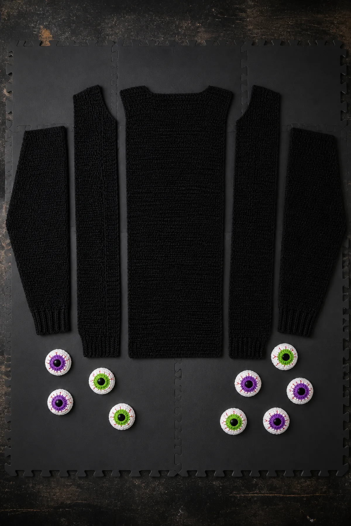 Blocked black cardigan panels and sleeves arranged before measured shoulder and side seaming