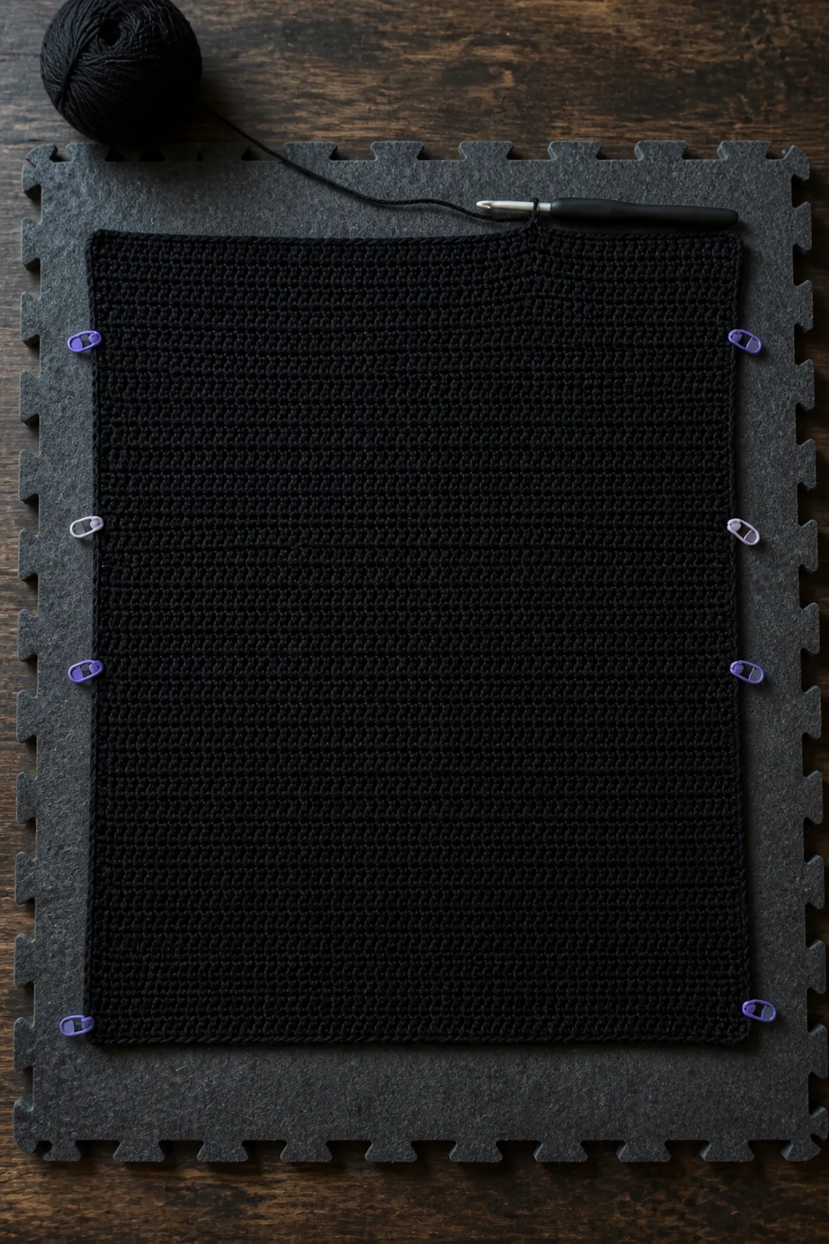 Black 72-stitch crochet cardigan back panel in progress with neat half double crochet rows